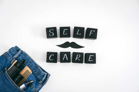 Men self care concept with blue denim jeans and set of male care products and devices and black block with text Self Care on white background.の写真素材