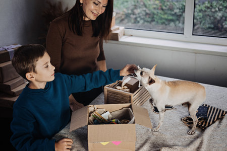 Happy family mom and kid putting bone in Pet Subscription Box for Dogs. Chihuahua dog and Subscription pet box with Organic Treats, Fun Toy, Bully Sticks, All-Natural Chews seasonal gearの写真素材