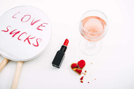Broken heart, Divorce and relationship family breakdown. Loneliness, couple break up, divorce concept with red lipstick text Love Sucks on mirror, glasses of rose wine and broken heart candy.の写真素材