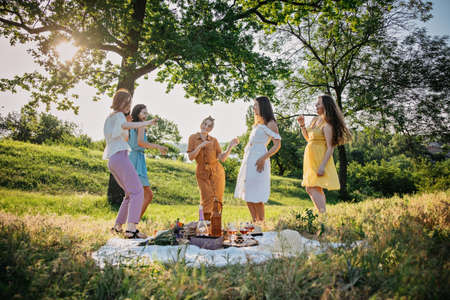 Galentines day. Slumber party. Summer Picnic Party Ideas, Outdoor Gathering with friends. Young women girl friends drinking wine, laughing, having fun together at picnic.の写真素材