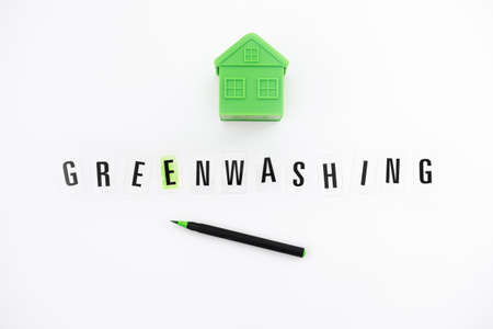 Greenwashing concept with green and black pen and plastic house. Greenwashing marketing ploy products seem more sustainable and environmentally friendly than they are.の写真素材