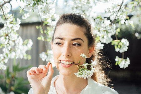 Spring is coming. Natural beauty. Beautiful young woman among white blossoms in spring garden. Young...