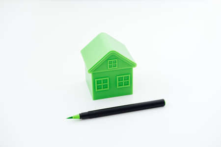 Greenwashing concept with green and black pen and plastic house. Greenwashing marketing ploy products seem more sustainable and environmentally friendly than they are.の写真素材
