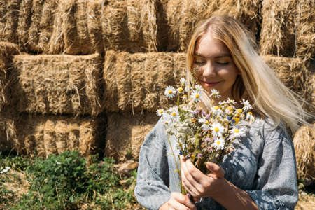 Cottagecore, simple living, country aesthetic lifestyle, modern rural fantasy, pastoral aesthetic. Young girl in peasant Cottagecore dress with wildflowers enjoying nature on country farmの写真素材