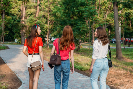 Group of girl friends jumping outdoors on sunset city public park. Young multi-ethnic hipster...
