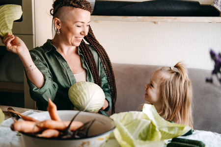 Happy vegan family mom and baby daughter cooking together and having fun on kitchen. Family cooking...