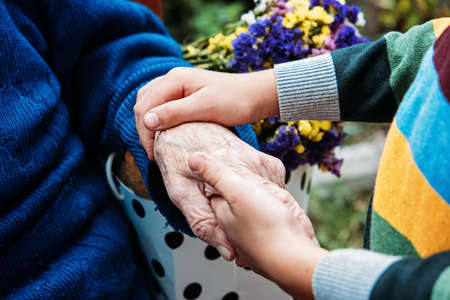 Charities for Elderly People. Young hands holding old elderly senior hands. Support for the seniors concept.の写真素材