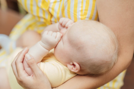 Newborn Baby Skin Care. Close up Mother holding newborn baby in hands on nature background. Outdoor...