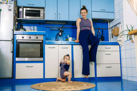 Little girl helps mom in the kitchen. Household chores, housekeeping for parentsの写真素材