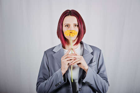 Unaltered candid portrait of young happy young woman with bright red hair with yellow flowerの写真素材
