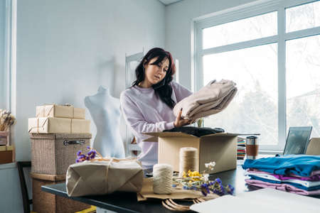 Small business owner woman packs the goods in eco packaging in office, shop.の写真素材