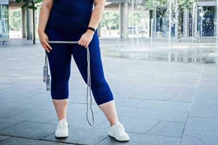 Faceless Plus size curvy happy young woman with skipping rope outdoors. Curvy Woman with Skipping...
