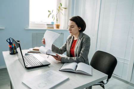 Young Businesswoman, manager sitting at table in office and do notes in diary and calendarの写真素材
