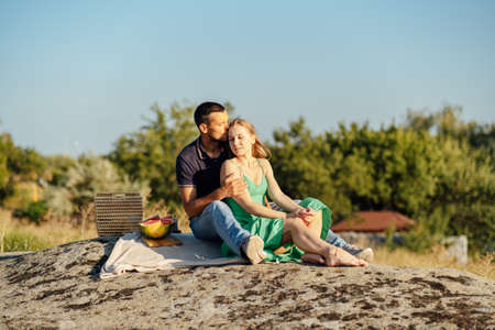 Happy loving couple kissing and having date outdoors. Young couple on summer picnic with watermelon.の写真素材
