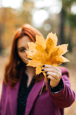 Autumn fashion, earth tones style, bright fall color palette. Portrait of red-haired girl in purple coatの写真素材