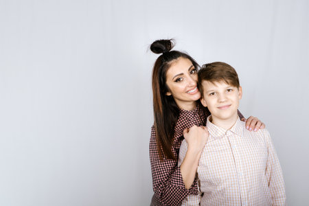 Parenting teen boys, Raising a teen. Studio portrait of Happy Teen boy hugging his momの写真素材