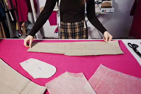 Seamstress working with sewing pattern on table in tailor shop
