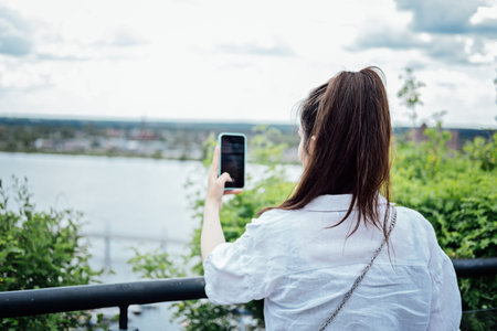 Young girl shooting photo or video on her mobile phone. Girl using her cell photo to catch the momentの写真素材