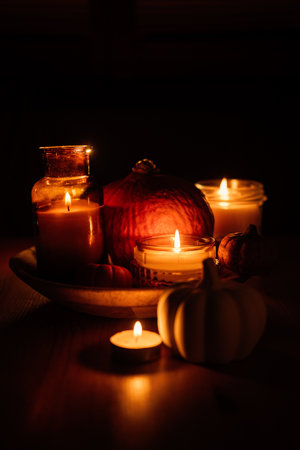 Autumn thanksgiving home decor with pumpkins and burning candles on table. Dark moody banner decorations with pumpkin and candlesの写真素材