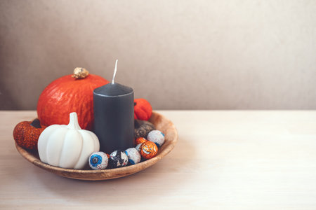 Sustainable Halloween. Eco-Friendly Halloween, plastic free trick-or-treating, Green Halloween. Zero waste Halloween decoration pumpkin, foil candy in wooden plate on tableの写真素材