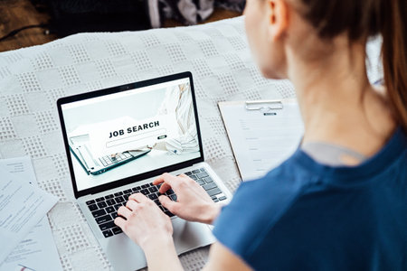 Job Search Career Recruitment Hiring Website Concept. Young woman in home browsing work opportunities online using job search web sites and applicationsの写真素材