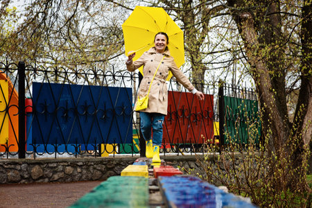 Autumn depression and how to deal with it. Seasonal affective disorder SAD. Happy senor woman in yellow rain boots and umbrella having fun and enjoy life in rainy autumn parkの写真素材
