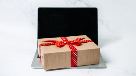 Tech gifts for Christmas for the tech-obsessed person. Gadgets and devices Xmas gift ideas. Laptop with Christmas Gift boxes on the tableの写真素材