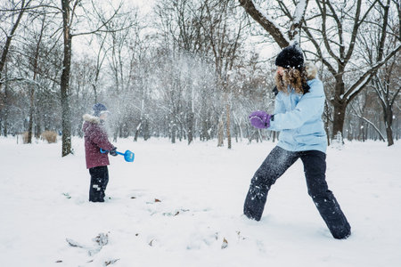 Outdoor winter activities for kids and family. Let it snow. Happy family Mom and kid boy having fun,...