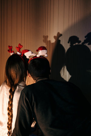 Merry Christmas and happy new year. Young couple in love celebrating Christmas or new year eve at home. Romantic couple in pajamas and Christmas reindeer antler headband hugging at home.の写真素材