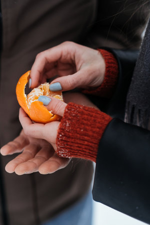 Outdoors Valentines Day Date Ideas for Couples. Winter love story. Cold season dating for couples. Young couple in love eating oranges, hugging and kissing in winter city street and parkの写真素材