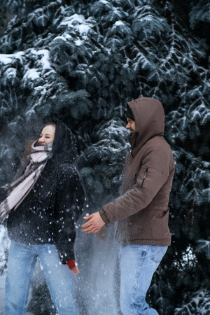 Valentines day outdoors celebration date ideas. Winter love story. Cold season dating for couples. Young couple in love play snowball, hugging and kissing in winter city street and parkの写真素材