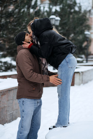 Outdoors Valentines Day Date Ideas for Couples. Winter love story. Cold season dating for couples. Young couple in love kissing in winter city street parkの写真素材