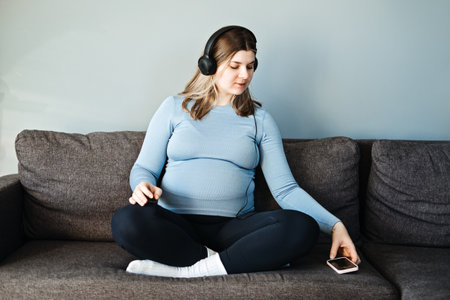 Pregnancy music for mother and unborn baby. Brain development. Relaxing and classical music for pregnant women. Pregnant woman with headphones listening music at homeの写真素材