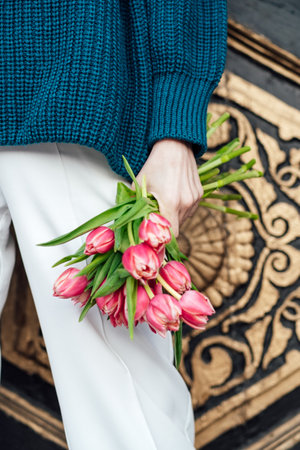 No face close up of pink tulips flowers bouquet in female hand outdoors. Unrecognizable woman holding in hands a bouquet of pink tulipsの写真素材