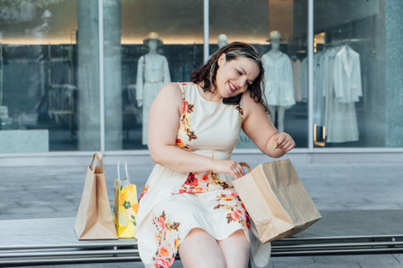 The Effects of Shopping on Mental Health. Understanding Compulsive Shopping Disorder. Shopaholic woman after multiple purchases in shopping bags outdoorsの写真素材