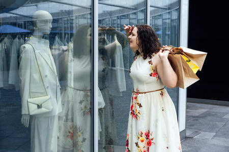 How to Shop for Summer Fashion on a Budget. Choosing the Right Fabrics for Hot and Humid Summer Weather. Outdoor portrait of stylish curvy woman with shopping bagsの写真素材