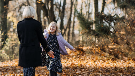 Ways for Kids and Families to Enjoy Autumn Outside. Fall activities for families with teenagers. Cute teen girl walking and playing with her mom on the Autumn natureの写真素材