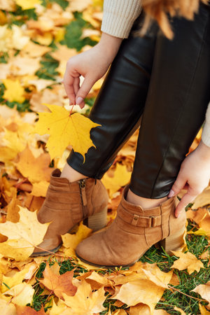 Autumn Shoes For Ladies, Styling Guide. How to prepare your shoes for autumn. Female legs in brown boots on autumn leaves backgroundの写真素材