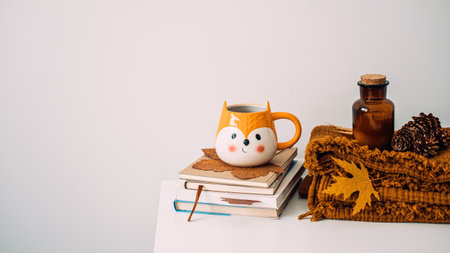 Autumn cozy home. Fall cozy reading comfort set with a blanket, books, candles, autumn fall leaves, cup of coffee on brown bed at white table. Cold season morning coffee, relaxing still life concept.の写真素材