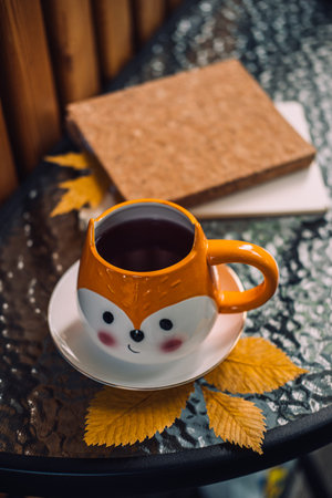 Autumn cozy still life on balcony, terrace. Fall cozy set with autumn fall leaves, cup of coffee or...