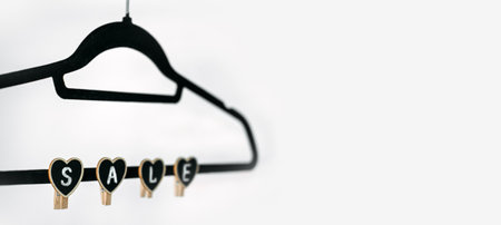 Black Friday Sale concept with black Clothes Hanger and heart shape sign SALE on white. Store, shopping concept, sale, design, empty hanger.の写真素材