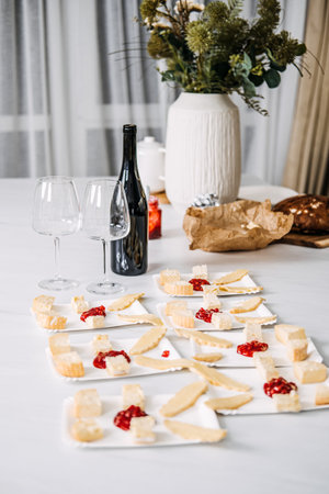 Wine Tasting Preparation with Cheese Pairings. Sommelier prepares for a wine tasting event, carefully pairing various cheeses with wines, featuring an unopened bottle and elegant glasses.の写真素材