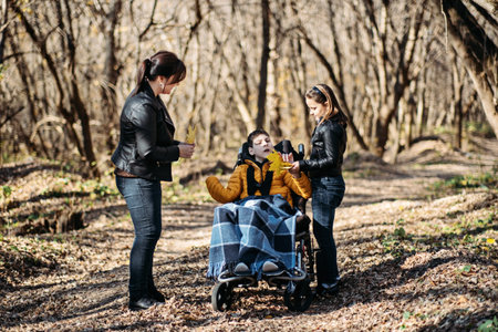 Mother and sibling supporting child in wheelchair during outdoor forest walk, special needs care,...