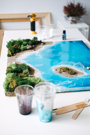 Exploring epoxy resin art with a DIY coastal landscape project in a bright workspaceの写真素材