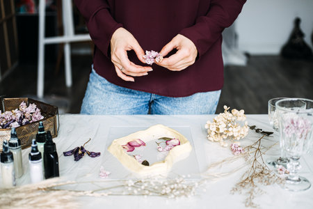 Hands arranging dried flowers for resin art, DIY craft project, floral preservation, creative hobby, handmade decor, artisan process, eco-friendly crafts, home art studioの写真素材