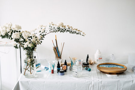 Art supplies and blooming branches on a workspace, set up for creative projects. Blending nature and art in a serene home studio environment.の写真素材