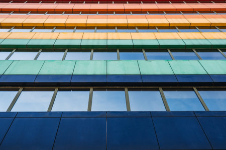 Colorful facade of modern building with horizontal stripes of red, orange, yellow, green, and blue. Urban architecture, geometric pattern, contemporary design, minimalism, city landscape.の写真素材