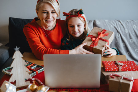 Mother and daughter celebrating Christmas virtually with loved ones. Virtual celebrations, online connections, holiday video calls, digital Christmas traditions, staying connected.の写真素材
