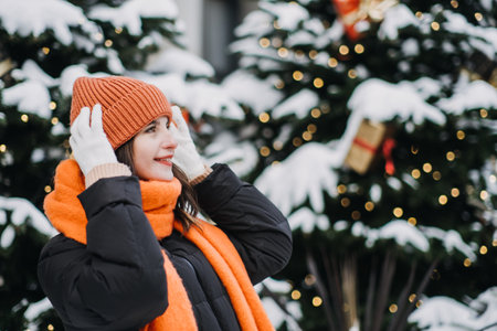 Woman smiling in festive winter setting, embracing mindful holidays and seasonal joy amidst Christmas trees and glowing lights.の写真素材