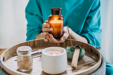 Young woman practicing self-care with aromatherapy and candles in a peaceful indoor setting. Relaxation and mindfulness concept.の写真素材